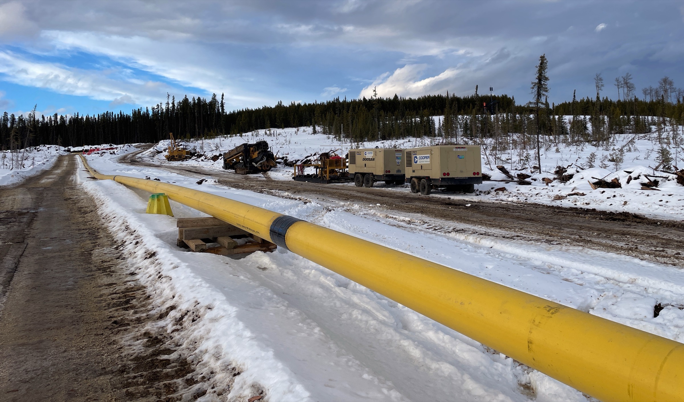 Aerial view of trenchless installation work on a forested slope, equipment on a narrow corridor