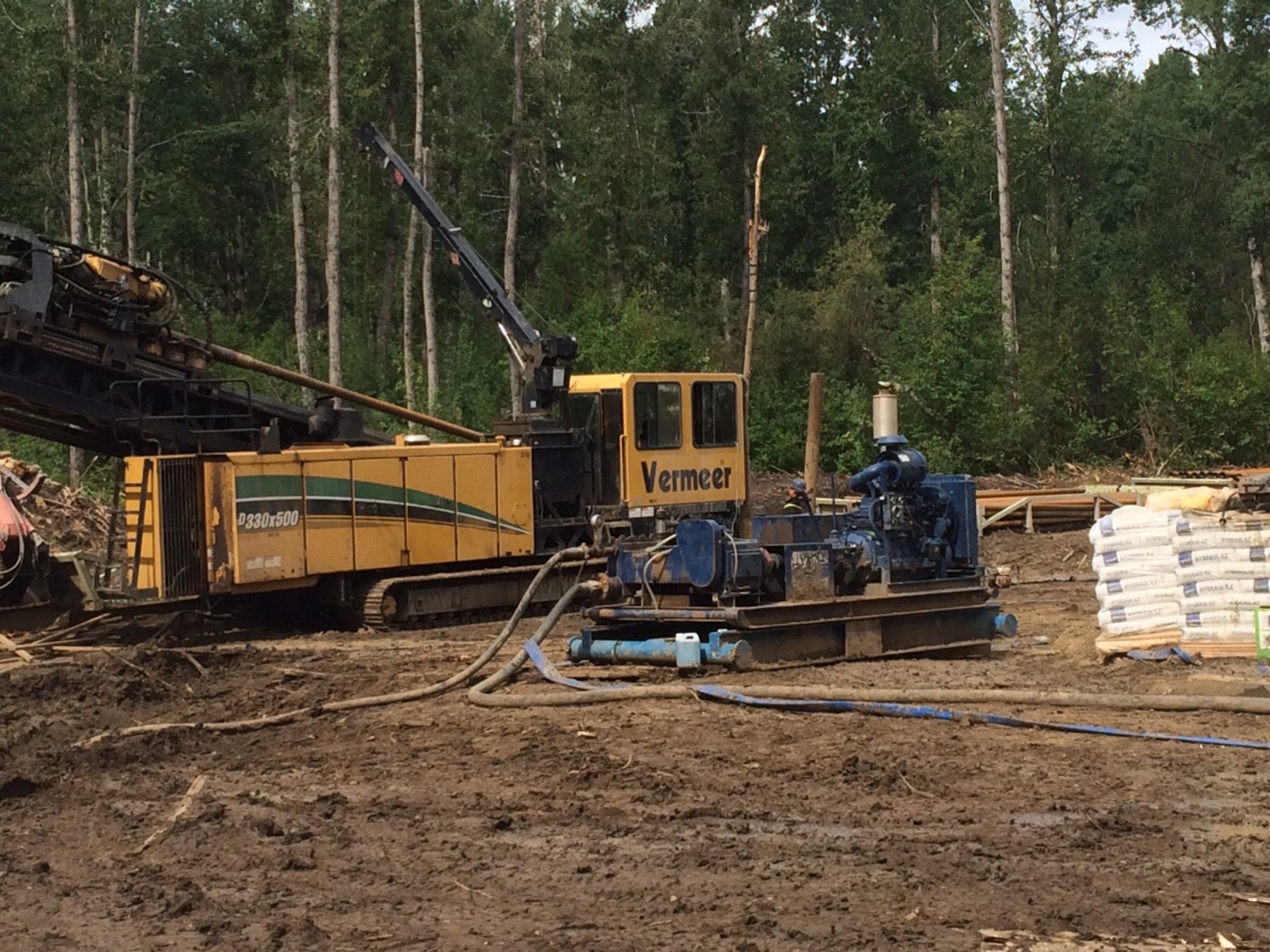 Two horizontal directional drilling rigs working side by side on a single narrow corridor